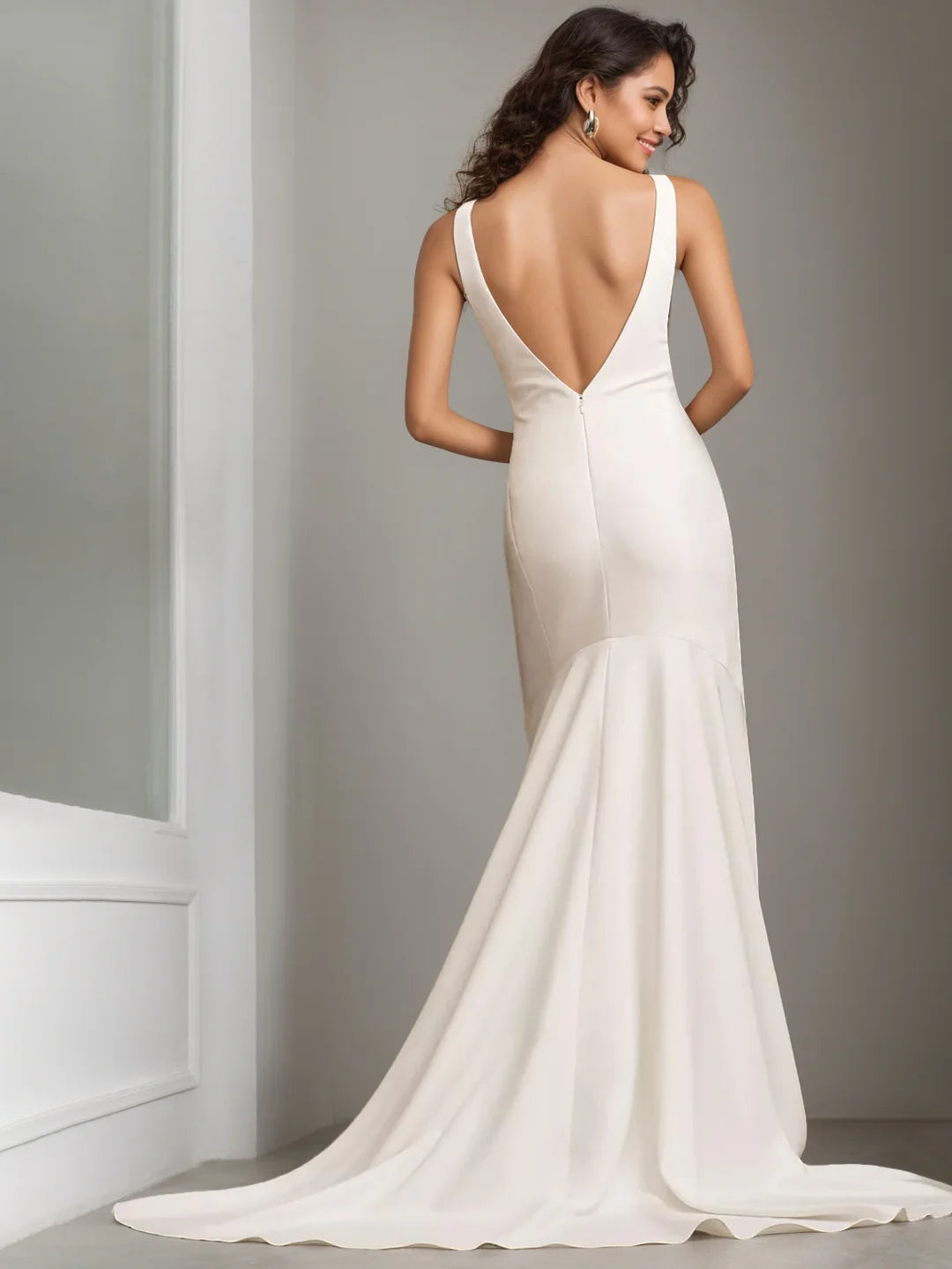 Vestido de novia moderno y minimalista color marfil, de corte sirena y largo hasta el suelo, con escote barco, sin mangas, espalda pronunciada y cola de capilla