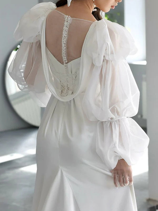 Romántico vestido de novia de satén corte sirena con escote cuadrado, mangas abullonadas transparentes y espalda con cordones