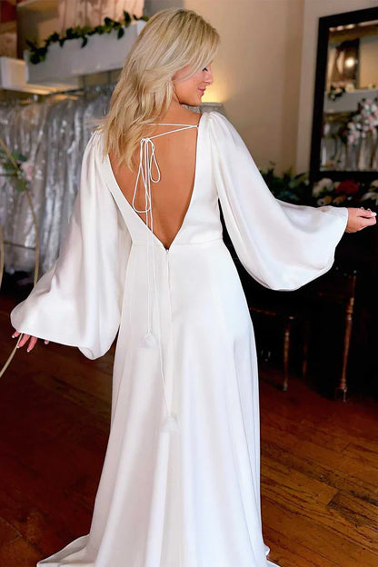 Vestido de novia de satén con escote en V profundo, mangas largas abullonadas, espalda descubierta con detalle de lazo, abertura alta y cola