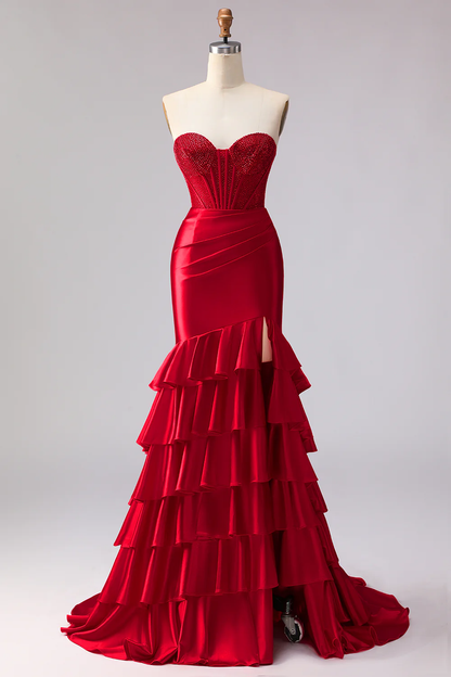 Glamuroso vestido de noche rojo corte sirena con corpiño de pedrería y abertura con volantes