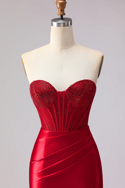 Glamuroso vestido de noche rojo corte sirena con corpiño de pedrería y abertura con volantes