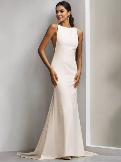 Vestido de novia moderno y minimalista color marfil, de corte sirena y largo hasta el suelo, con escote barco, sin mangas, espalda pronunciada y cola de capilla