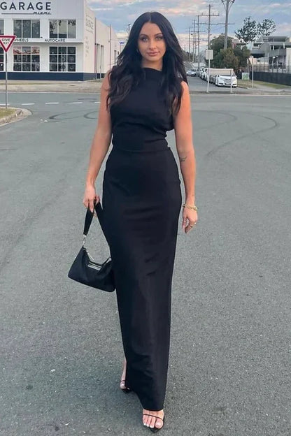 Vestido de noche negro con espalda descubierta, mangas casquillo y silueta hasta el suelo