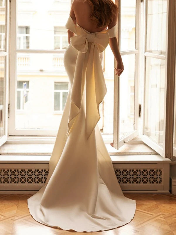 Vestido de novia de satén con hombros descubiertos, lazo extragrande en la espalda, silueta de sirena y cola catedral