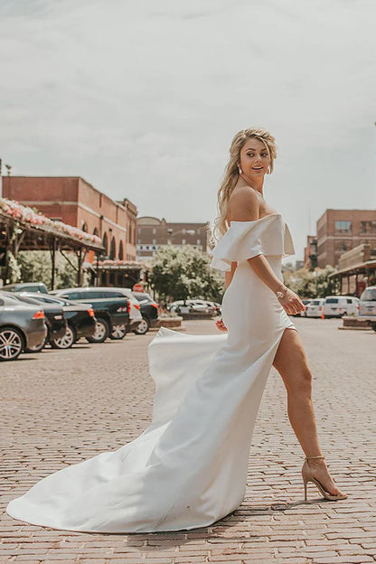 Vestido de novia con hombros descubiertos, corpiño de volantes, abertura alta y cola de tul desmontable