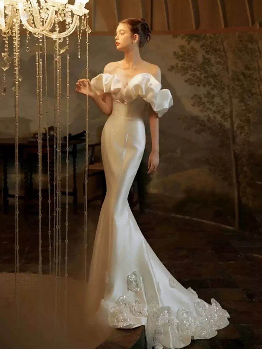 Romántico vestido de novia de satén corte sirena extragrande con hombros descubiertos, volantes, cola con pedrería y espalda baja